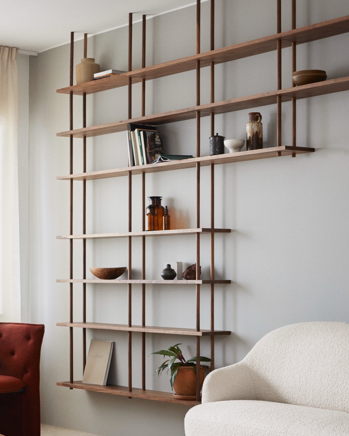 A walnut Bond shelf hanging from the ceiling in a living room