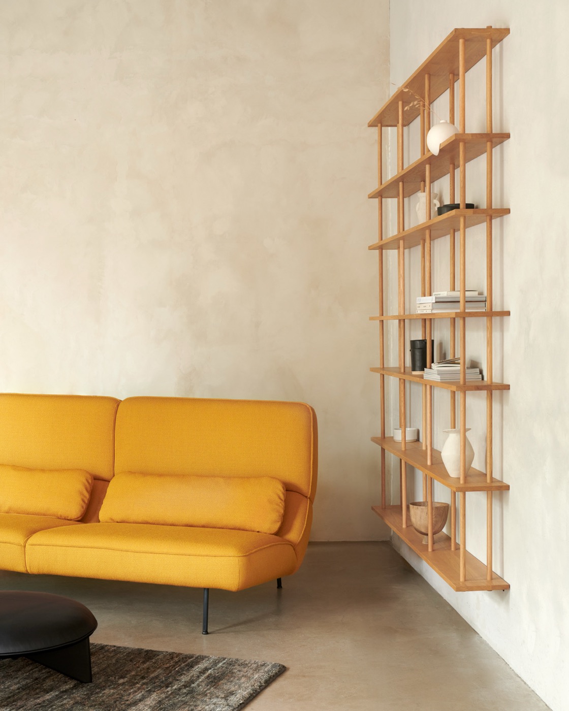 A tall Bond shelf on a wall beside a yellow sofa